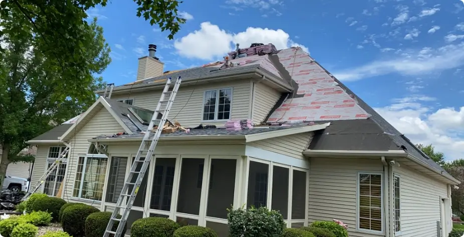 view of beige house with residential roof being repaired after storm damage